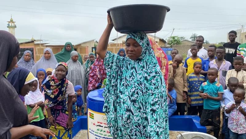 Frau schöpft Wasser am fertigen Brunnen (Togo)